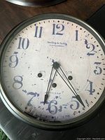 Front view of vintage wall clock face showing worn aged dial and large Arabic numerals.