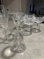 Photo showing the variety of nine crystal stemware glasses arranged on a counter including tall glasses, short dessert glasses, and cut glass glasses.