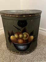 Full front view of vintage hinged storage chest showing hand-painted bowl of assorted fruits on lower front panel and metal latch at center.