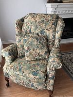 Front view of floral tapestry wingback chair showing overall condition and cabriole legs