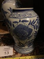 Front and side view of rounded ceramic vase with intricate blue floral and wave patterns on white background.