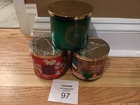 Lot of three candles positioned in a triangle on a wooden floor, showing tops and sides of each candle.