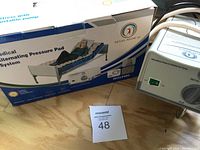 Photo of boxed mattress system with model illustration lying on mattress and visible air pump unit.