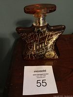 Star-shaped amber glass perfume bottle with gold script 'Amber Bond NYC No. 9' on front, nearly full with liquid inside.