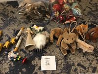 First photo shows all ornaments laid out on carpet including bagged colorful balls, bottle brush animals, wooden candles, stars, angel, and nutcracker figure.
