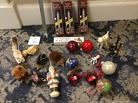 Overview of assortment of Christmas ornaments including bottle brush animals, balls, Santa figurine, and decorative bows