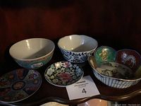 Photo showing all five decorative bowls with oriental themes arranged together on a wooden surface.