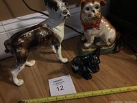 Photo showing two metal Boston terrier figurines and one small black ceramic Scotty dog alongside ceramic French bulldog figurine with red bow.