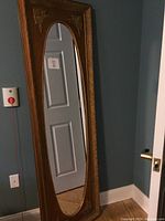 Full view of the carved gold-red frame with oval mirror showing size and reflection.