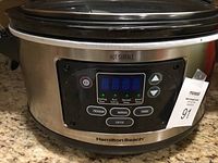 Front view of Hamilton Beach crock pot showing digital control panel with buttons for program, manual, probe, and enter, temperature and time display, stainless steel exterior, and side clip.