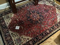 Wide view of the red oriental area rug with floral medallion and geometric patterns showing the general design and color scheme.