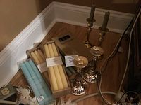 Photo showing candlesticks and multiple packs of taper candles in various colors including yellow, blue, and sage green.