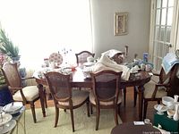 Dining table with leaf installed surrounded by six chairs, decorative items on top.
