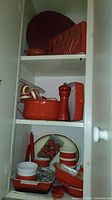 General view of cabinet with red enamel pieces, spoons and placemat