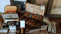 Overview of jewelry boxes containing earrings, cufflinks, rings, brooches, lighters and watch faces on dresser