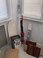 Full view of all items including vacuum, ironing board, speaker box, blinds, roller shade, and laminate tiles