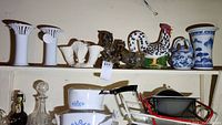 Shelf with various ceramics including white fluted vases, owl and rooster figurines, small shell-shaped vases, and CorningWare dishes below