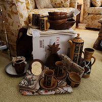 Photo showing collection of vintage Crown Devon Aztec ceramic pieces alongside wood dishware and linens on box in living room setting