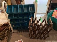 Front view of metal hardware sorting rack with blue plastic compartments and wooden expandable wine rack side by side in basement.