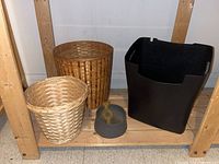 Photo showing two wicker baskets, one large black plastic basket and a grey dog bowl with a toy inside, displayed on wood shelving.