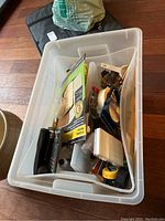 Overview of plastic bin filled with assorted hardware, tools, and household items showing varying smaller items inside the bin.