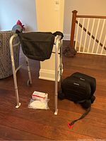 Aluminum Pro Basics walker with black fabric bag, Harmony child booster seats, and disposable masks on floor