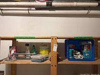 Wide view of basement wooden shelves with household cleaning supplies and blue crate with light bulbs.