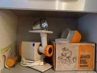 Main unit of Moulinex electric meat grinder with attachments and original box on shelf.