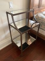 Side table from an angled front view showing metal frame and mirrored shelves