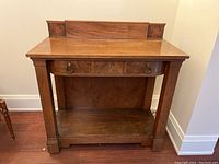 Full view of the wood sideboard facing forward showing the veneer top, three dovetail drawers with metal ring pulls, and lower shelf with scratches.
