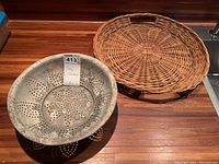 Both the aluminum colander and wicker tray placed side by side on a wooden counter