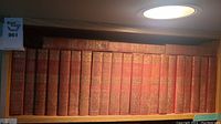 Front-facing view of the spines of a collection of 23 red hardcover books with gold embossed floral patterns and titles by Robert Louis Stevenson.