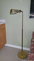 Full view of the brass arched floor lamp standing next to a wooden cabinet and couch.