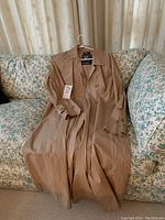 Full view of tan trench coat draped over couch