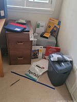 Full view of file cabinet, paper shredder, Kodak photo paper, Kinko's paper pack, and Herschel iPad sleeves on top of file cabinet and floor.
