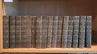 Full front view of all 16 volumes representing the entire Irving's Works Westchester Edition book set arranged on a wooden shelf with visible gold embossed titles and floral spine decorations.