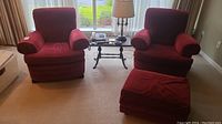 Two red armchairs and matching ottoman positioned in living room