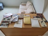 Wide angle photo showing the assortment of books, catalogues, and clippings laid out on a wooden surface
