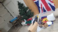 Wide view showing artificial Christmas tree, card table, chairs, Halloween decorations, boxes, and Royal Doulton platter and placemats on table