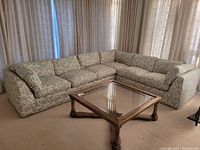 Two piece sectional sofa in L-shape with floral upholstery and cushions, photographed front view with wooden coffee table in front.