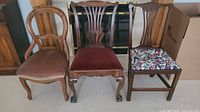 Three antique chairs side by side, showing different upholstery and backrest designs.