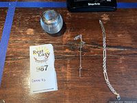 Sterling silver candle holder, chain and bracelet shown together on wooden surface, chain appears tangled.