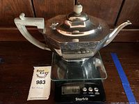 Full side view of octagonal sterling silver teapot on scale