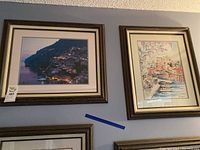 Two framed pictures hanging on a wall, one a nighttime photo and the other a watercolor painting depicting Positano, Italy.