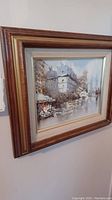 Wide angled photo of framed oil painting depicting a scenic architectural and natural setting with human figures.