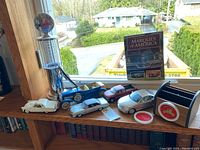 Overall lot on the window ledge showing all model cars, book, and collectibles.