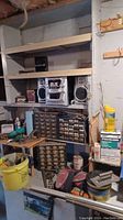Photo of wooden shelving unit containing plastic hardware drawers, stereo system, various tools and home upkeep supplies.