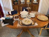 The full selection of soup tureen, serving dishes, plates, trays, and accessories displayed on a wooden table.