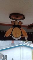Ceiling-mounted vintage swag light with stained glass petal shade, shown from below in a room with window view.