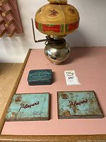 Overview of all items including three vintage cigarette tins and Budweiser lamp on wood surface